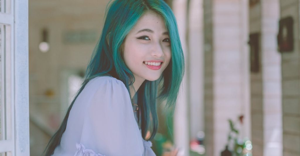 Beautiful young woman with vibrant green hair smiling happily indoors.